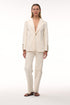 Woman wearing an ivory canvas blazer with hand-embroidered sleeve details and matching trousers.